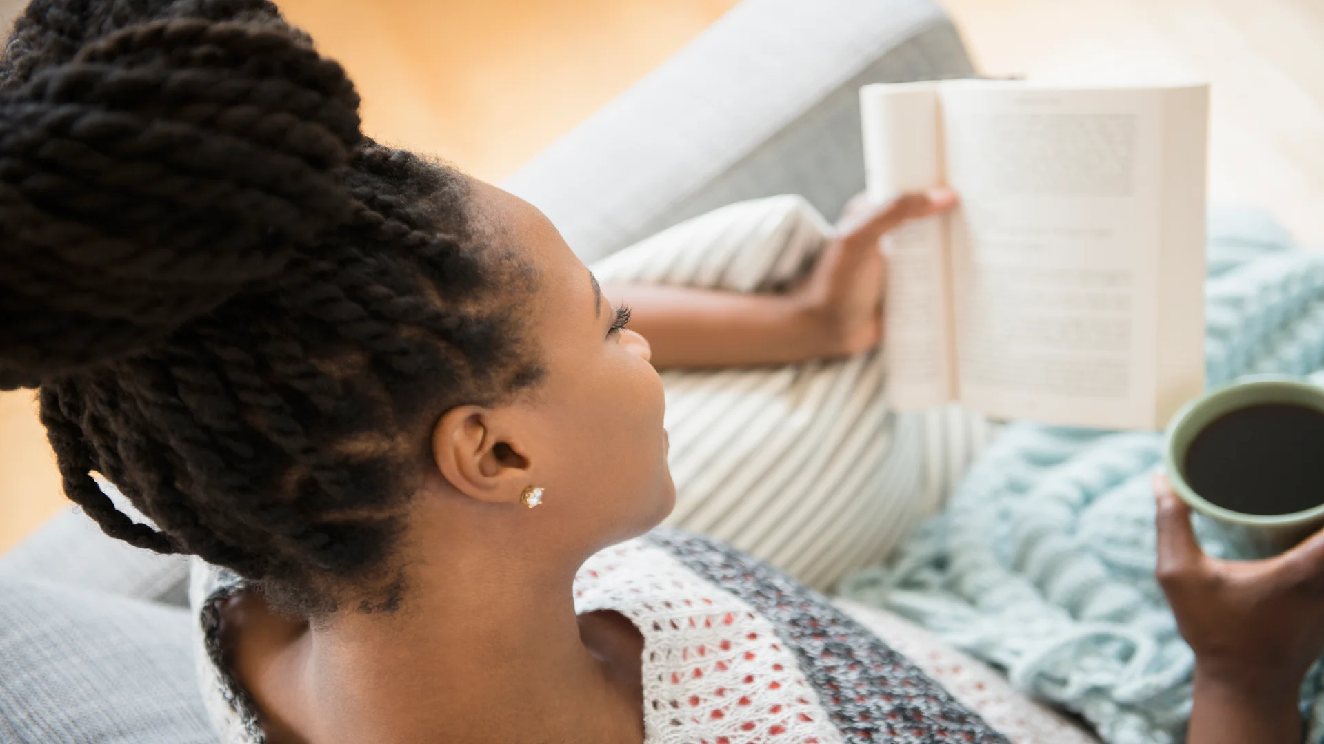 A woman sitting on top of a bed reading.