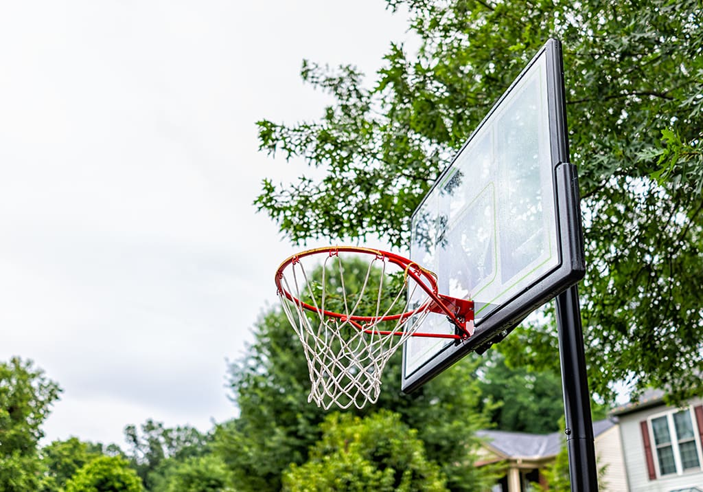 A basketball hoop with the net up and trees in the background.