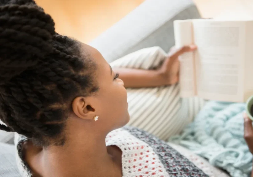 A woman sitting on top of a bed reading.